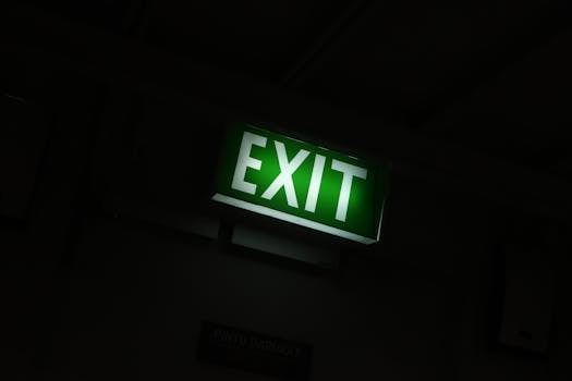 A glowing green exit sign provides guidance in a dimly lit indoor space.