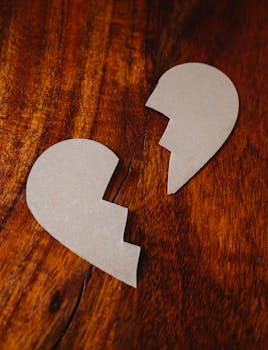Cardboard broken heart symbol on wooden table, representing love and separation.